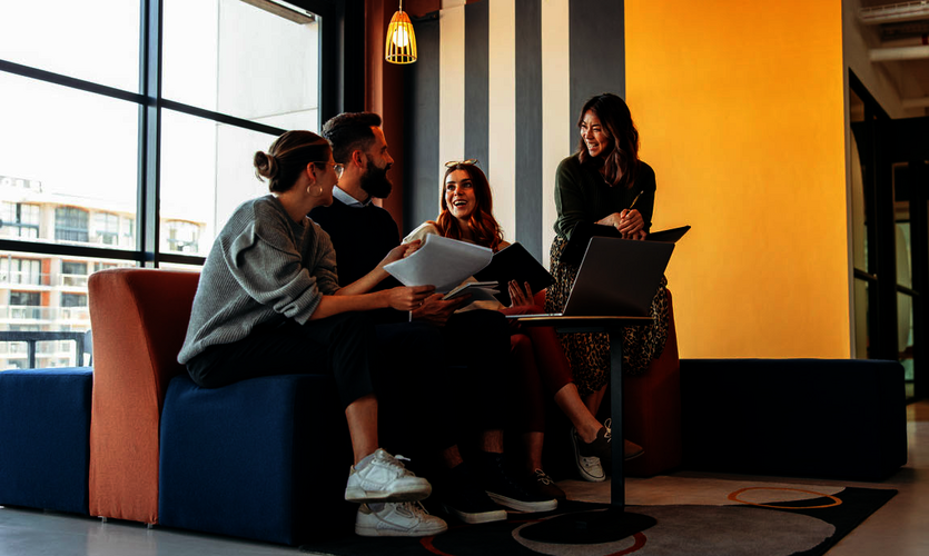 Three young women and a man sitting on a sofa in front of a laptop.