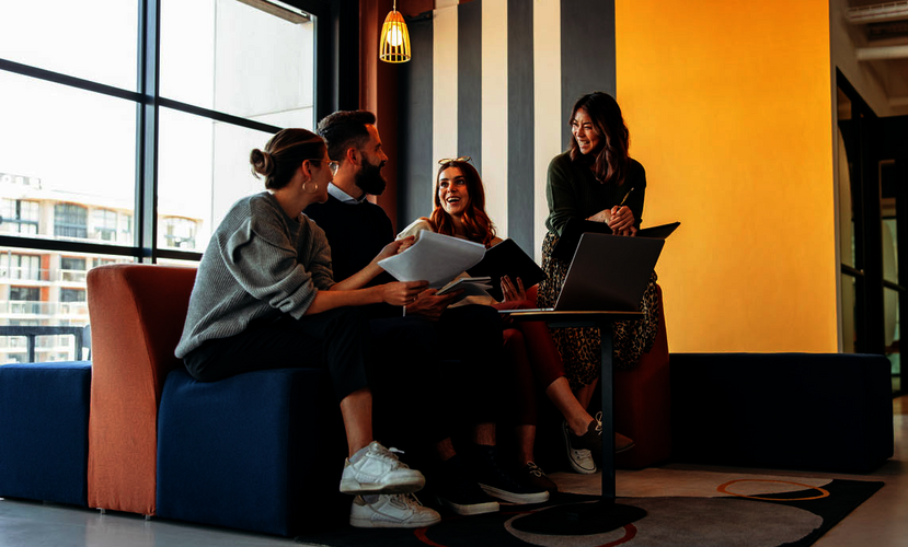 Tres jóvenes mujeres y un hombre sentados en un sofá frente a un portátil.